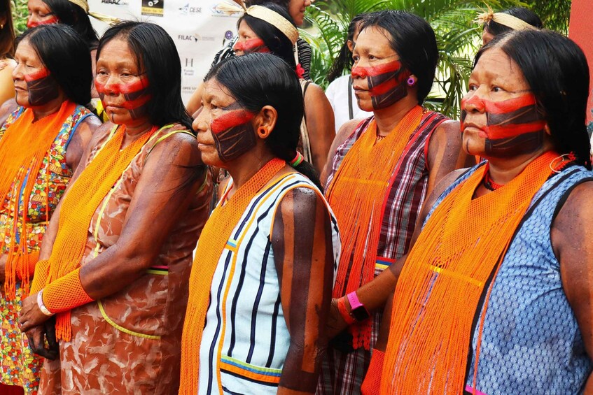A group of people wearing traditional attire with orange sashes and face paint. 4