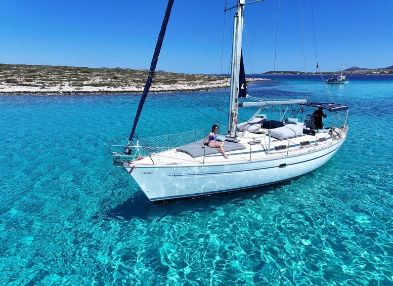 A sailboat named 'Seagull' anchored in clear turquoise waters with a person on deck. 1