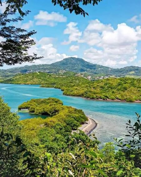 A coastal landscape with clear turquoise waters, lush greenery, and a winding road. 4