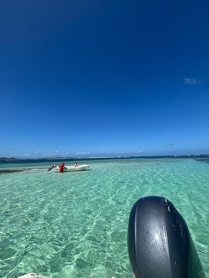 A clear blue sea with a boat carrying two people. 3