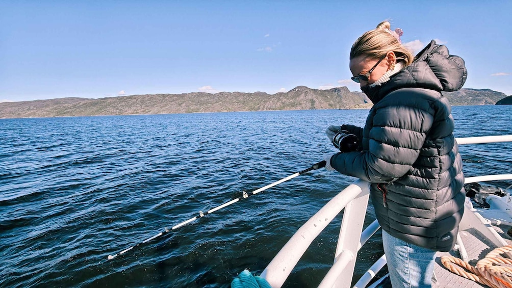 A person fishing on a boat with a mountainous landscape in the background. 5