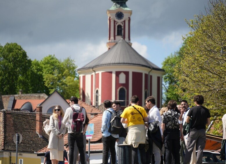 A group of people gathered around a historical building with a clock tower. 2