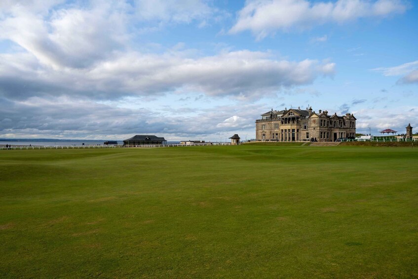 A golf course with a large clubhouse and a distant body of water. 5