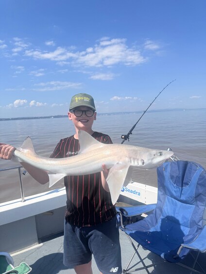 A person holding a large fish on a boat with a clear sky in the background. 5