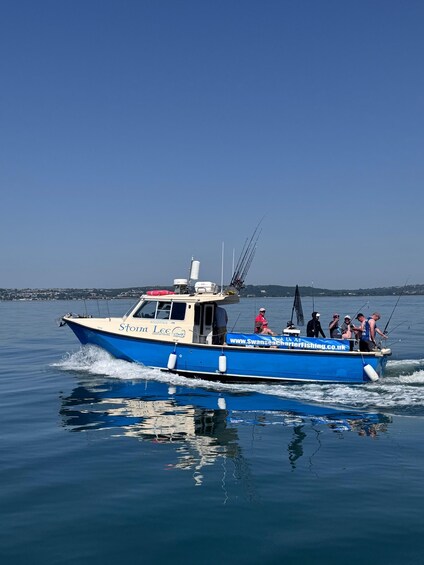 A blue and white boat named 'Storm Lee' with several people fishing on board. 1