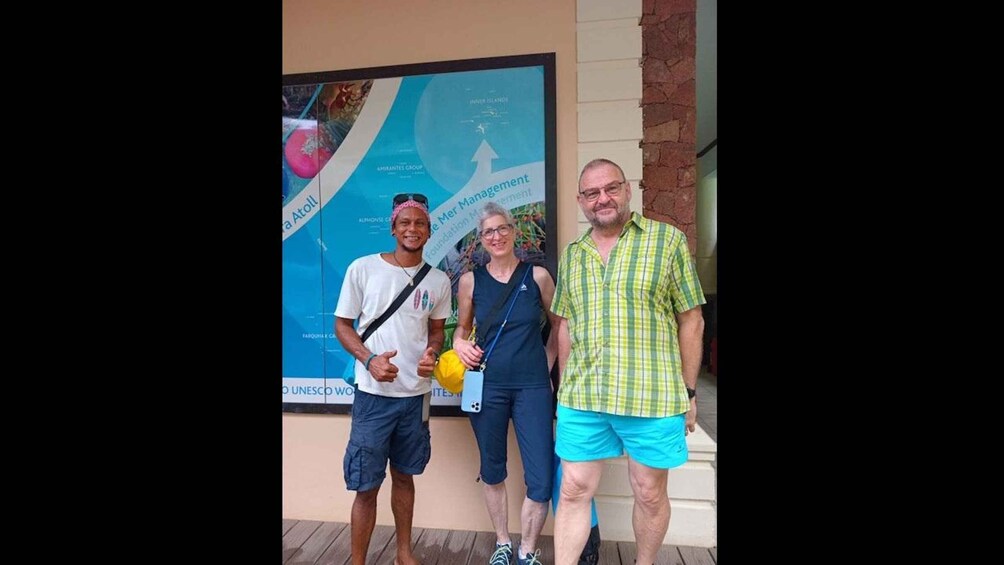 Three people standing in front of a poster with text and graphics. 4