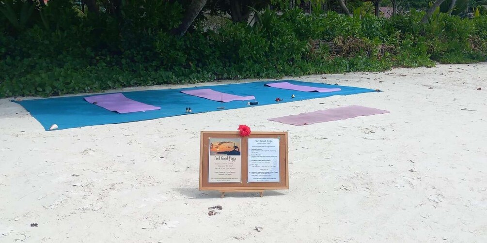 A beach with yoga mats laid out and a signboard with yoga instructions. 5
