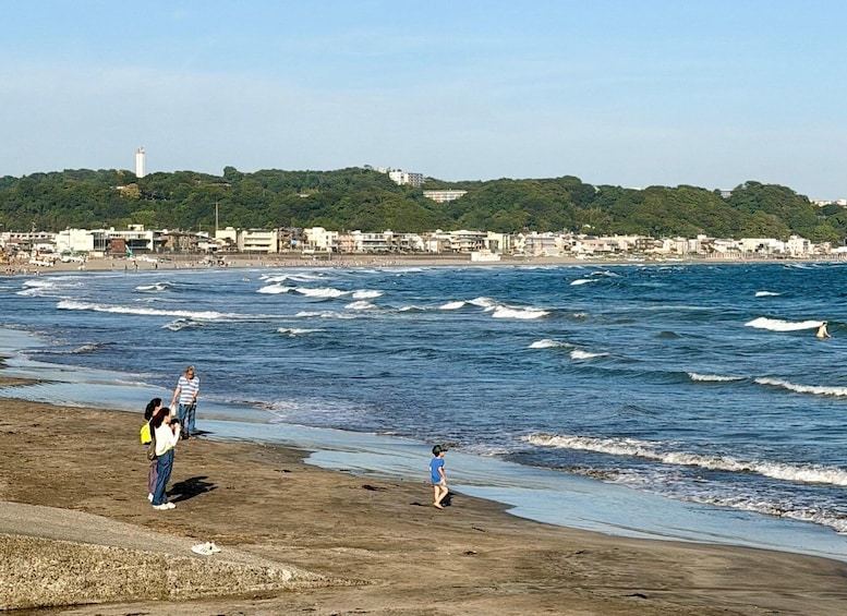 A beach with waves, people, and buildings in the background. 5
