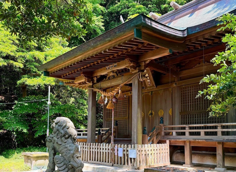 A traditional Japanese building with a wooden structure, a stone lion statue, and lush greenery in the background. 2