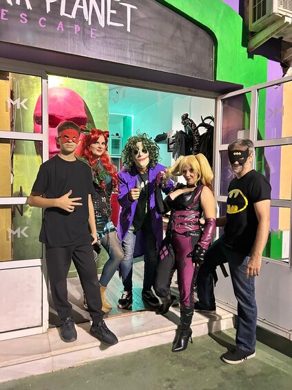 A group of people in costumes standing in front of a building with a sign that reads 'ESCAPE PLANET.' 1