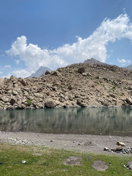 A mountainous landscape with a clear lake, rocky terrain, and sparse vegetation. 4