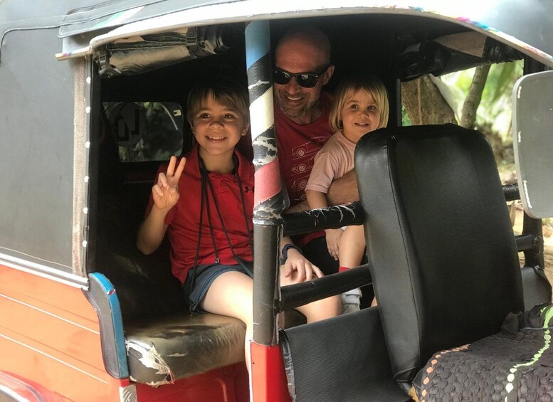 A vehicle with two passengers and a driver, one child in a red shirt and the other in a pink shirt, seated in the front. 5