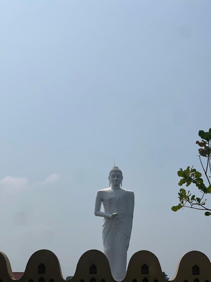 A large white statue of a seated figure with a pointed top, standing on a curved base. 3