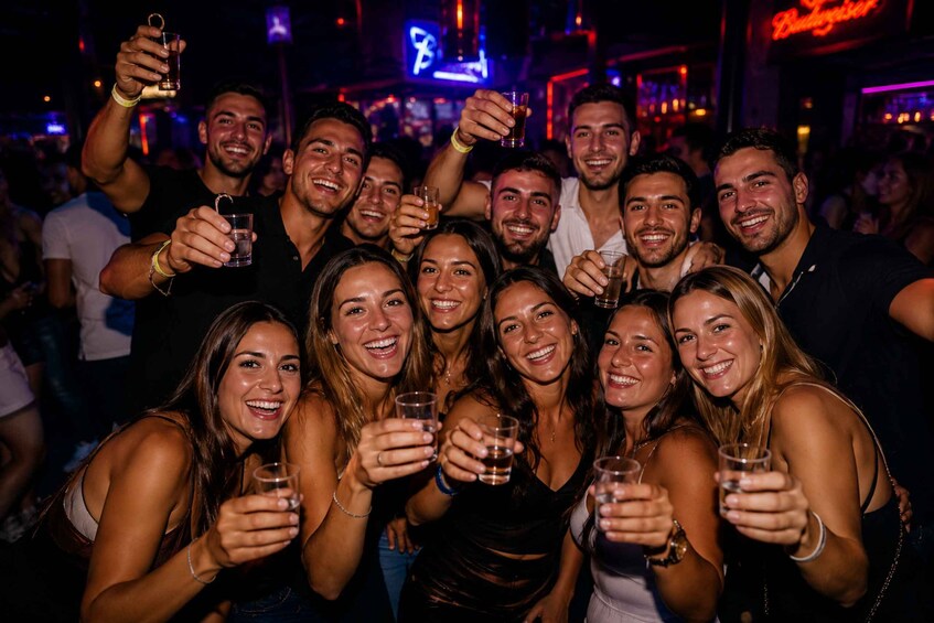A group of people holding drinks in a dimly lit indoor setting. 3
