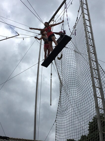 Two individuals performing an aerial acrobatic routine on a netted structure. 3