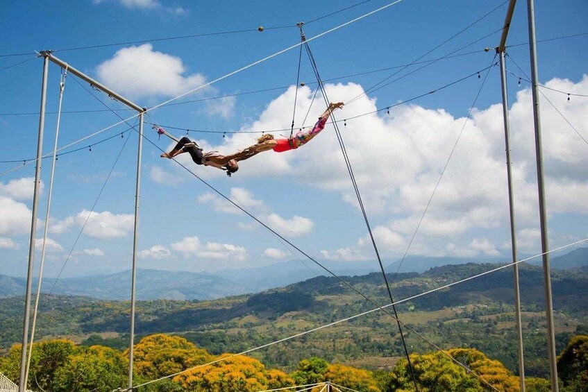 A trapeze artist performing high above a mountainous landscape. 1