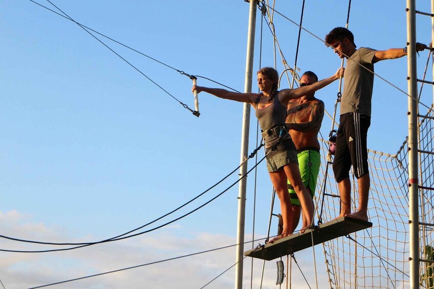 A person on a rope bridge with another person assisting. 5