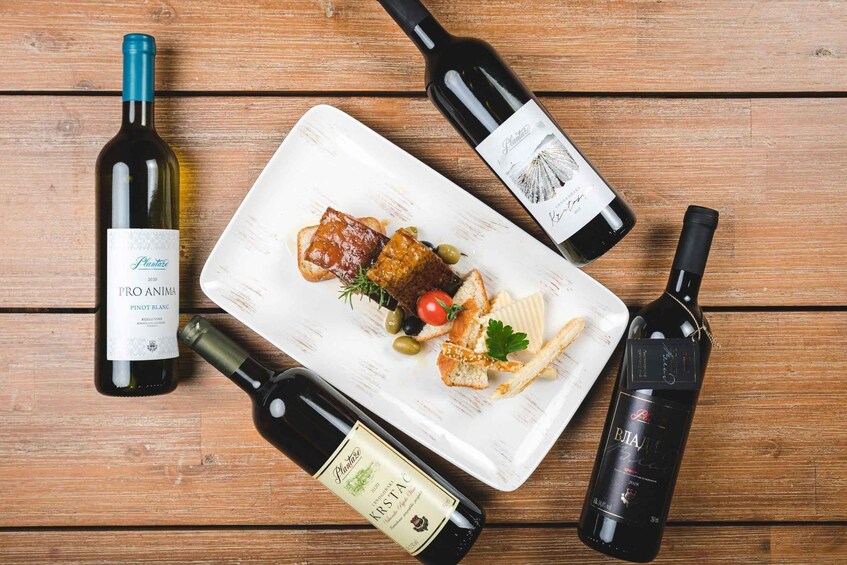 Three wine bottles and a plate with food on a wooden table. 2