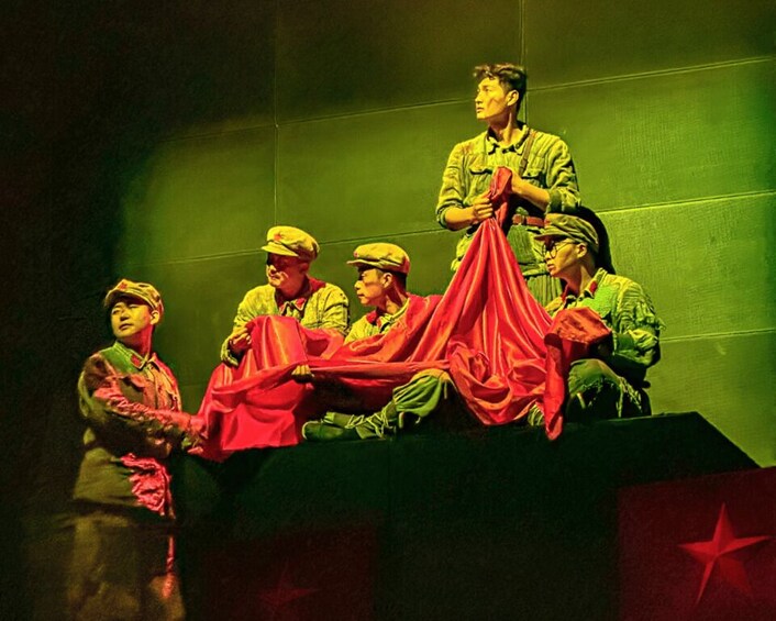 A group of people in military uniforms sitting on a stage with a red cloth. 3