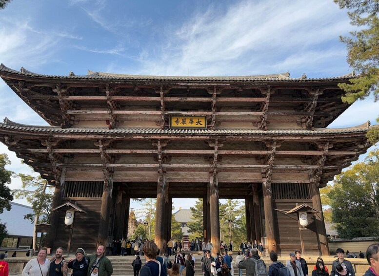 A traditional Japanese gate with a sign, surrounded by visitors. 4