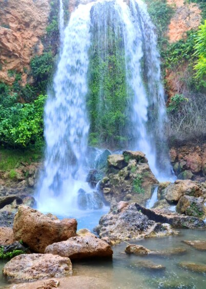 A waterfall cascading over rocks in a forested area. 2