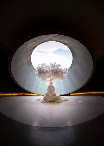 A meditative figure under a circular structure with a tree. 1