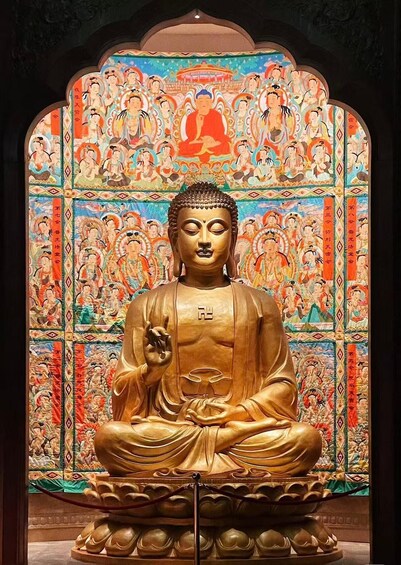 A golden Buddha statue in a meditative pose, surrounded by a colorful mural with traditional figures. 2
