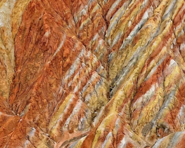 A close-up of a textured surface with a pattern of interlocking, wavy lines in shades of orange, yellow, and gray. 2