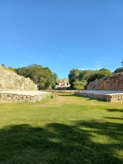 An ancient stone structure with a central building surrounded by stone walls and grassy areas. 3
