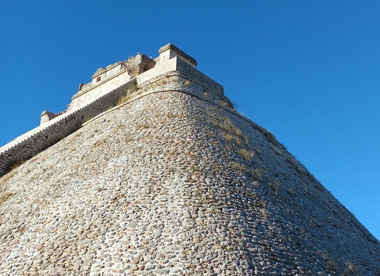 A stone tower with a crenellated top and a clear blue sky in the background. 1