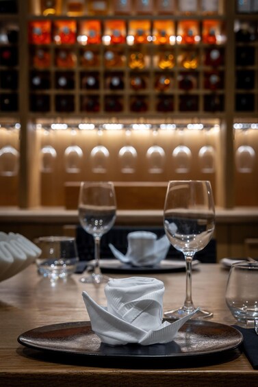 A bar setting with empty glasses, a folded napkin, and a bottle of water on a wooden table. 3