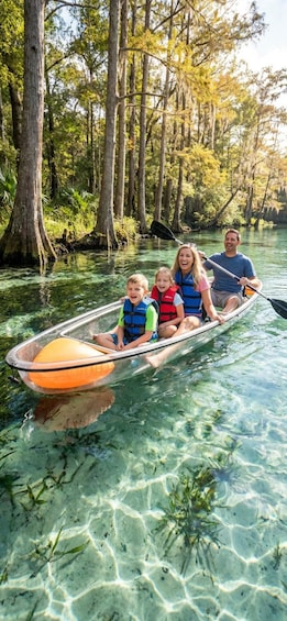 A family in a canoe on a clear river surrounded by trees. 3