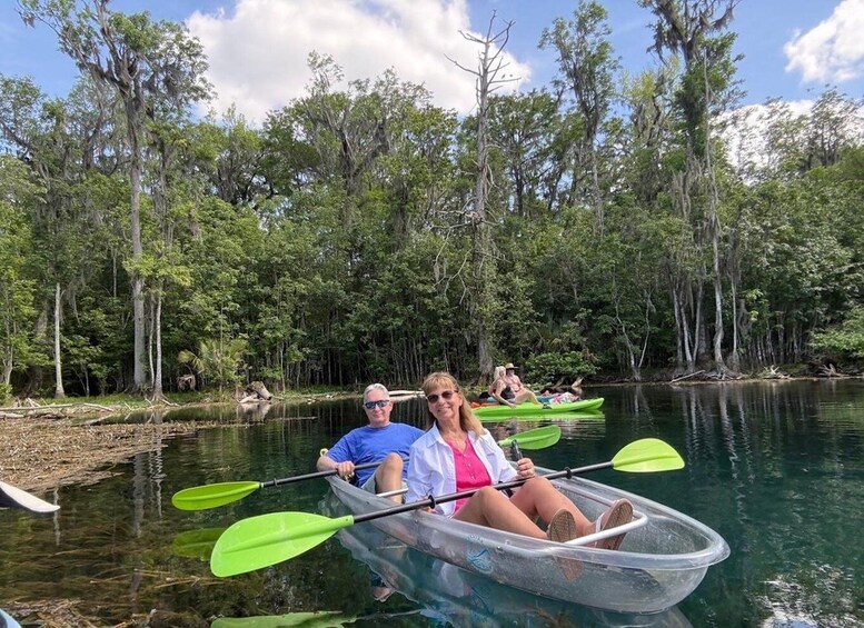 People kayaking on a calm river surrounded by dense forest. 1