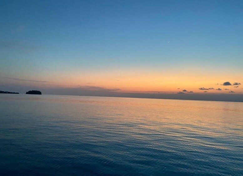 A calm sea at sunset with a small island in the distance. 1
