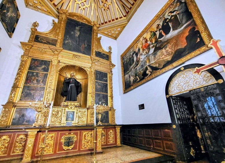 An ornate church interior with a central statue, gilded altars, and a large religious painting. 2