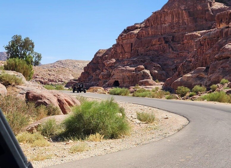 A winding road through a desert landscape with red rock formations and sparse vegetation. 4