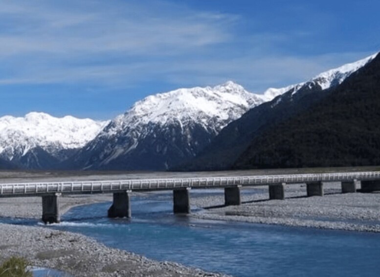 A bridge over a river with snow-capped mountains in the background. 3
