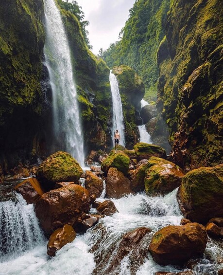 A waterfall cascading over moss-covered rocks in a narrow canyon. 5