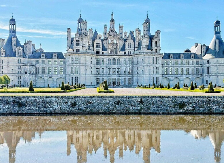 A grand château with a symmetrical façade, a moat, and a clear reflection in the water. 4