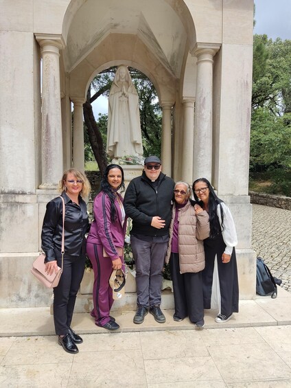 A group of people standing in front of a statue under a stone archway. 2