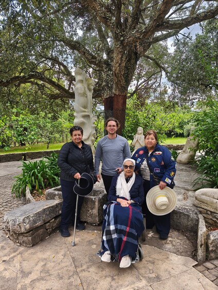 A group of people in a park with a large tree and statues. 5
