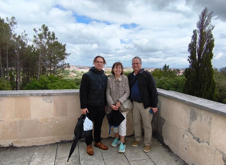 Three people standing on a rooftop with a cityscape and trees in the background. 3