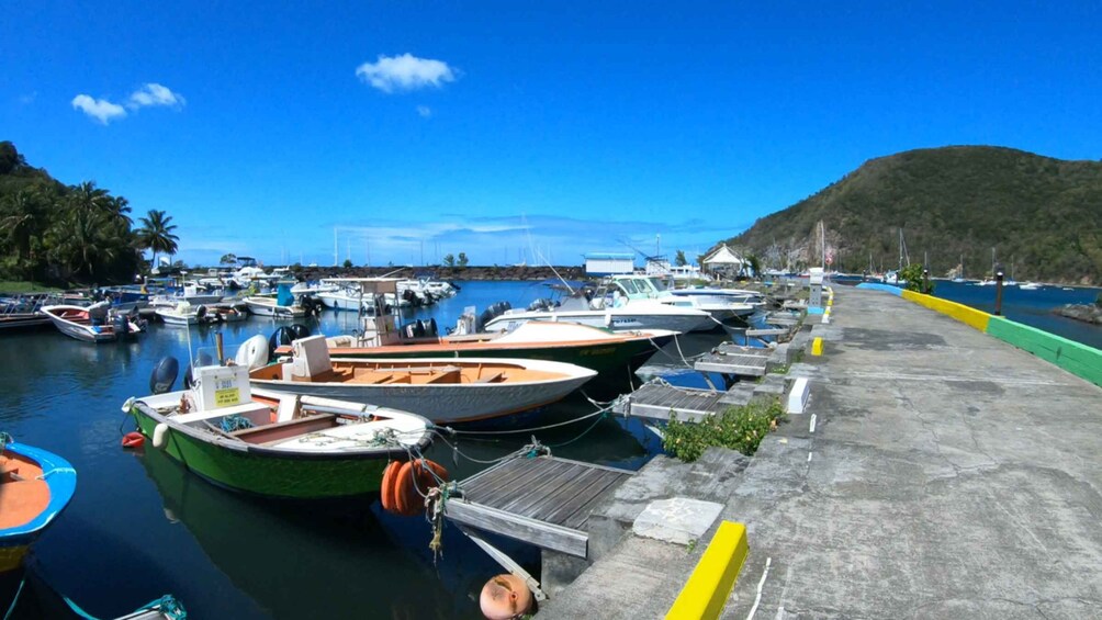 A marina with various boats docked, a concrete dock, and a hilly landscape in the background. 2