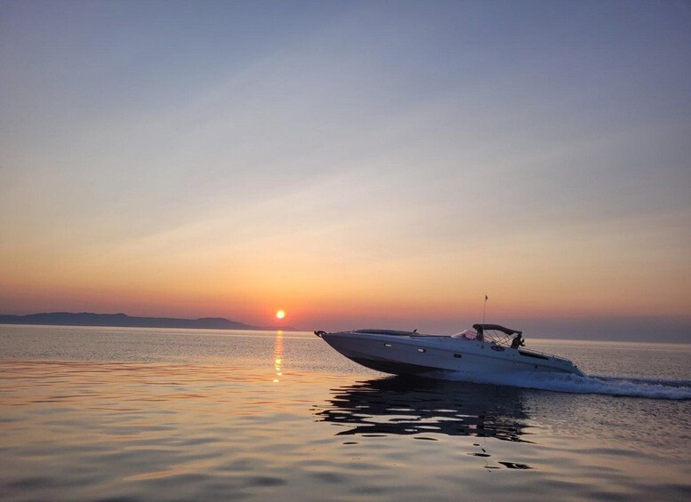 A speedboat on calm water during sunset with a clear sky. 1