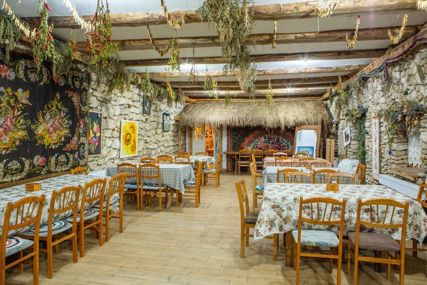 A rustic dining area with wooden tables, chairs, and a stone wall. 5