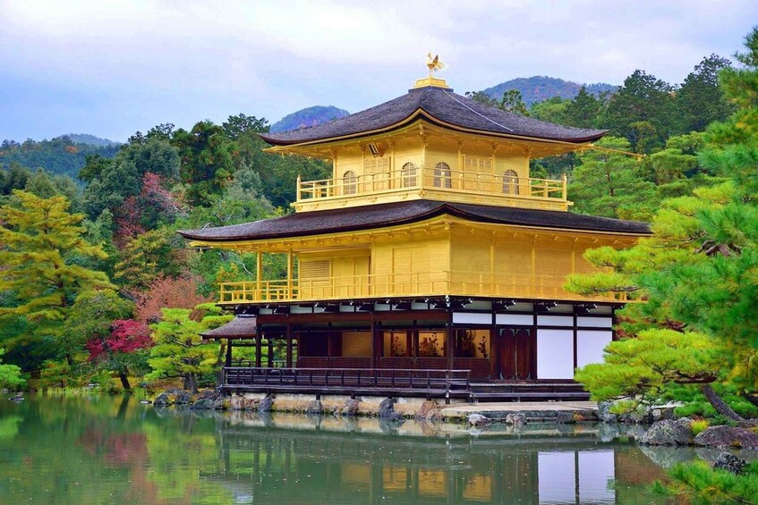 A traditional Japanese pagoda with a reflection in the water, surrounded by lush greenery and mountains. 1