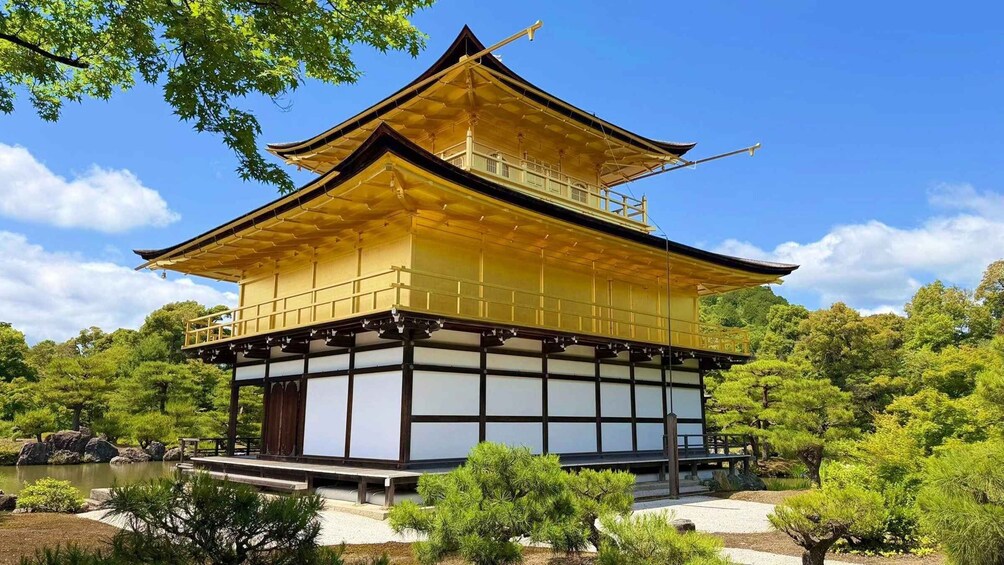 A traditional Japanese pagoda with a golden roof, surrounded by lush greenery and a clear blue sky. 4