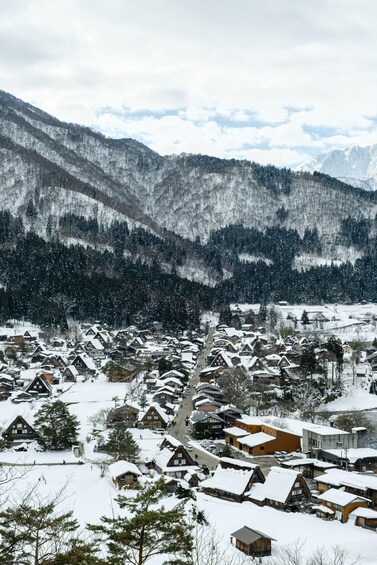 A snow-covered village with traditional houses nestled in a mountainous area. 1