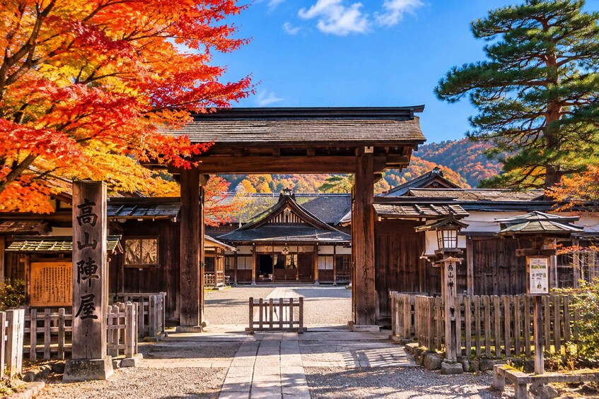 A traditional Japanese temple with autumn foliage, wooden structures, and a clear sky. 3