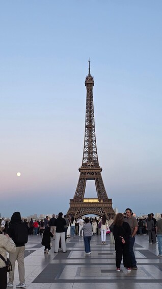 The Eiffel Tower with people walking around it. 1